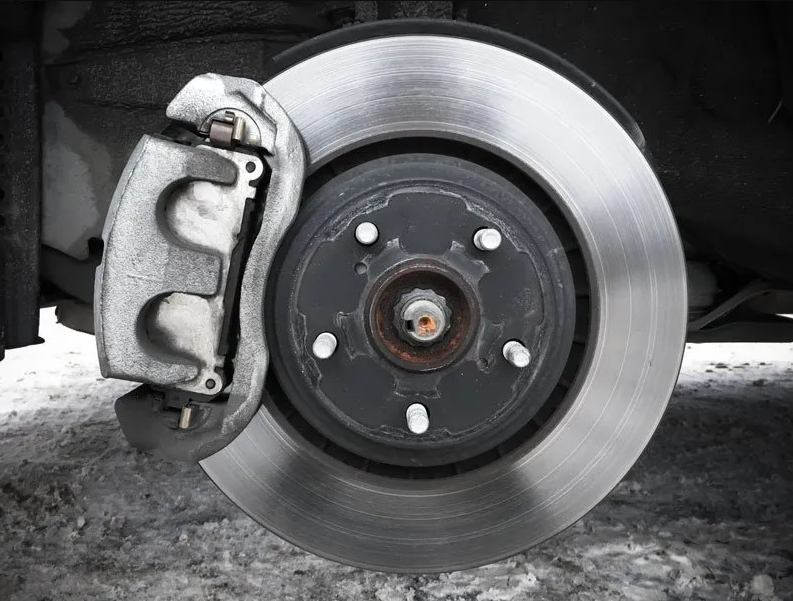 Mobile brake repair technician inspecting brake rotors and calipers on-site
